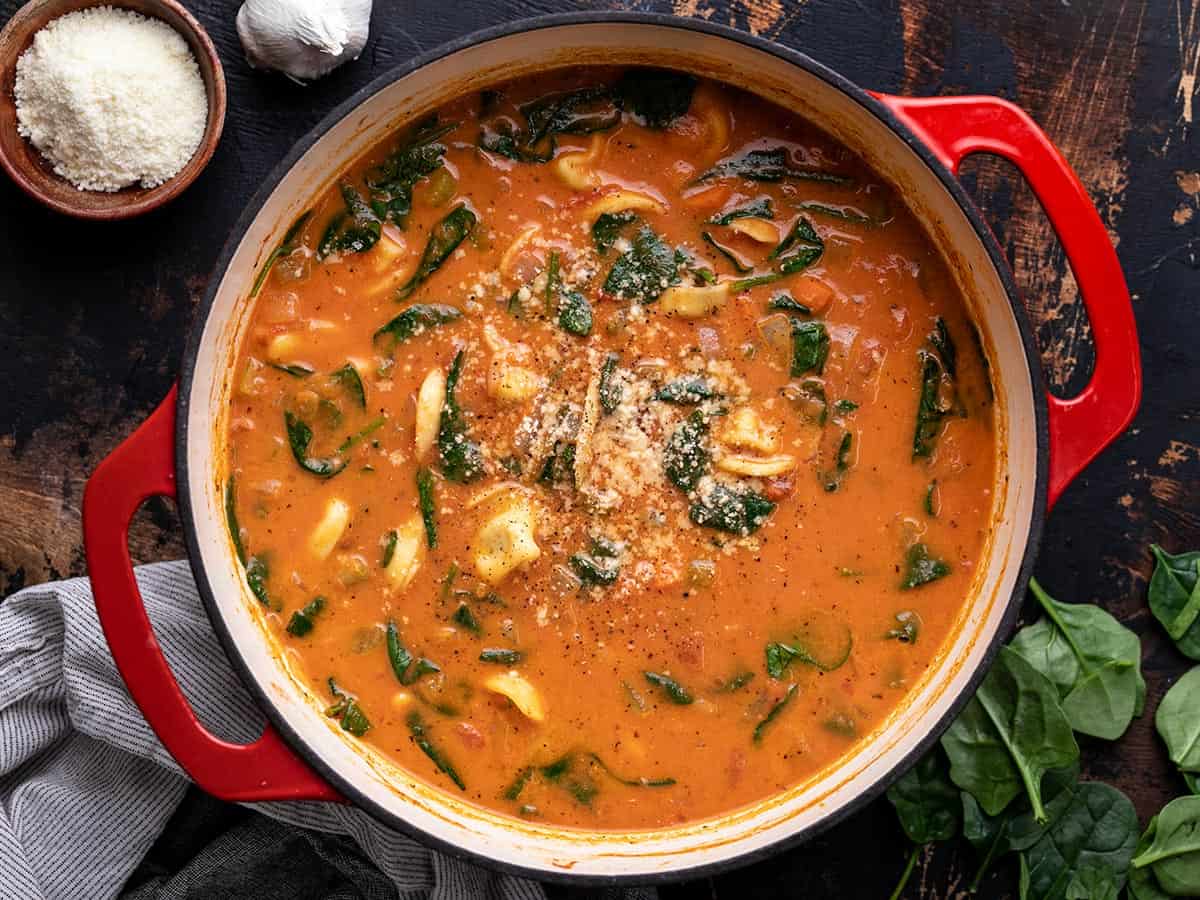 Overhead view of the finished pot of creamy tortellini soup garnished with Parmesan and pepper.