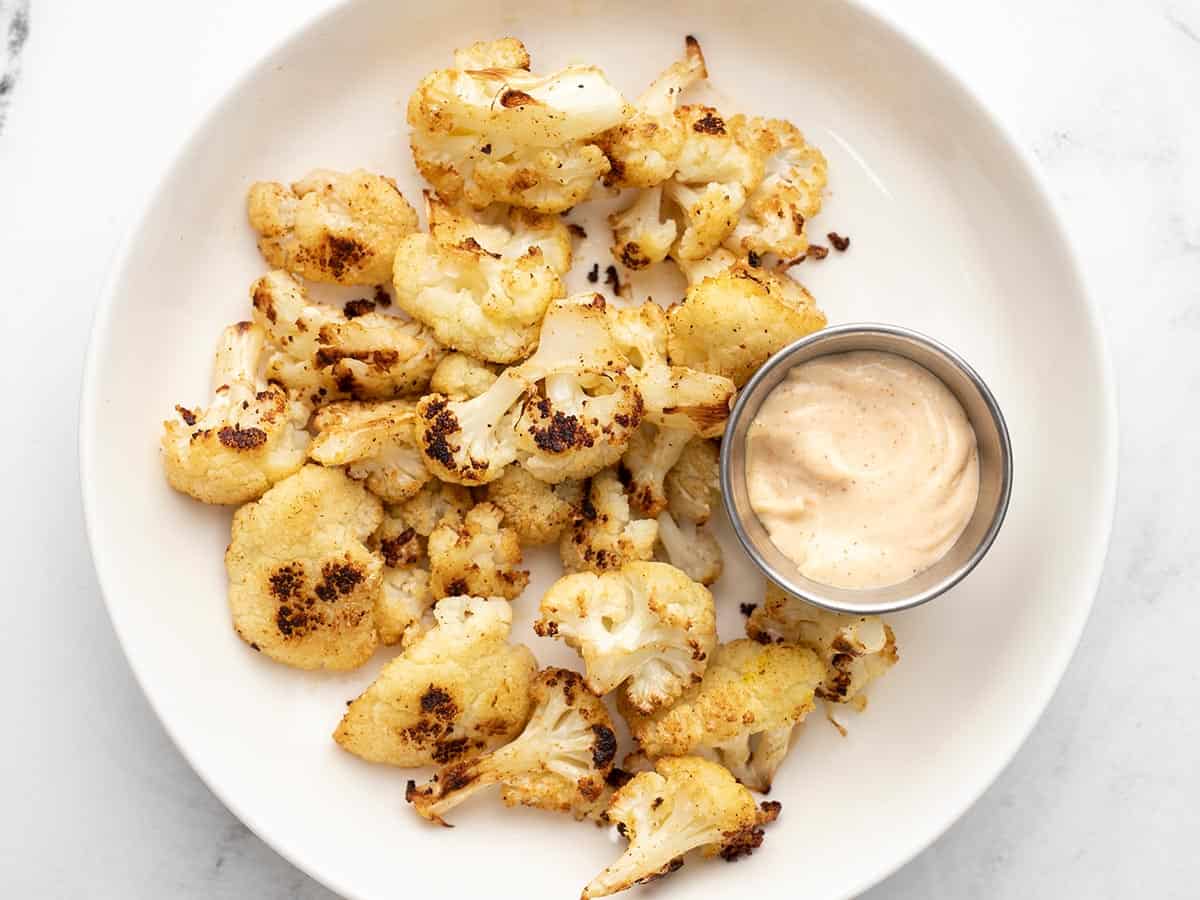 A plate full of Cajun Roasted Cauliflower with dipping sauce.