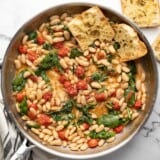 Finished white beans in the skillet with garlic bread in the side.