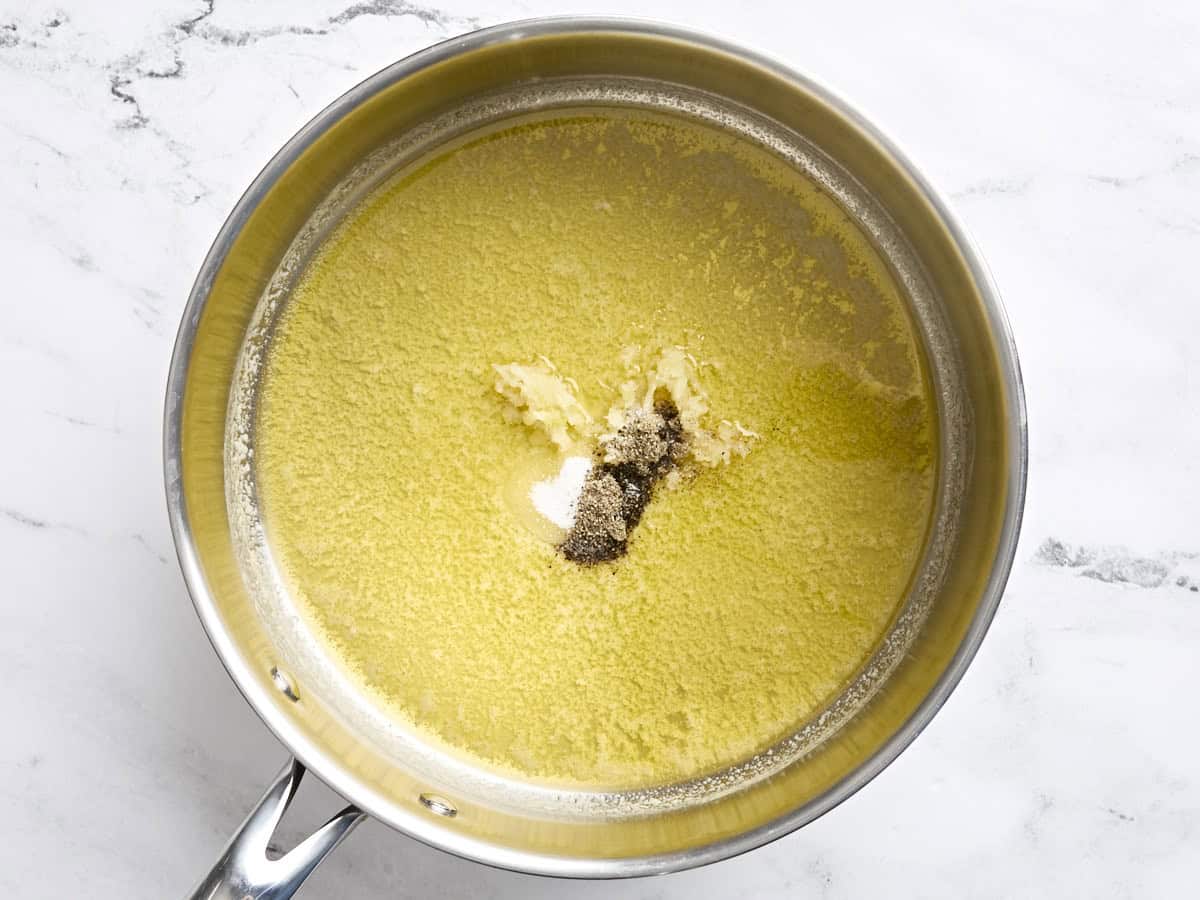 Melted butter in a skillet with salt, pepper, and minced garlic.