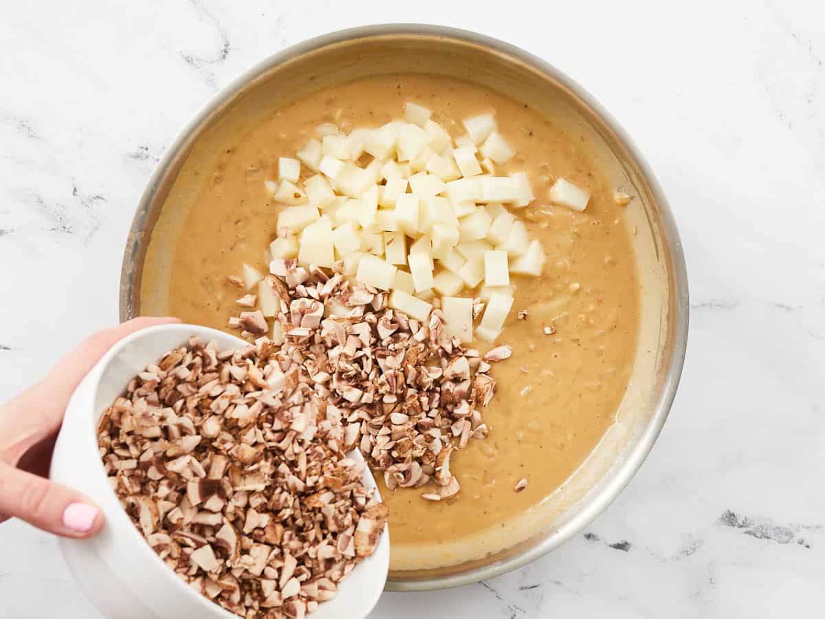 Diced potato and mushrooms added to the sauce filling for a vegetarian pot pie in a skillet.