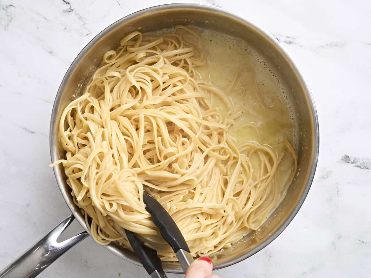 Fettuccine being tossed in a homemade alfredo sauce,