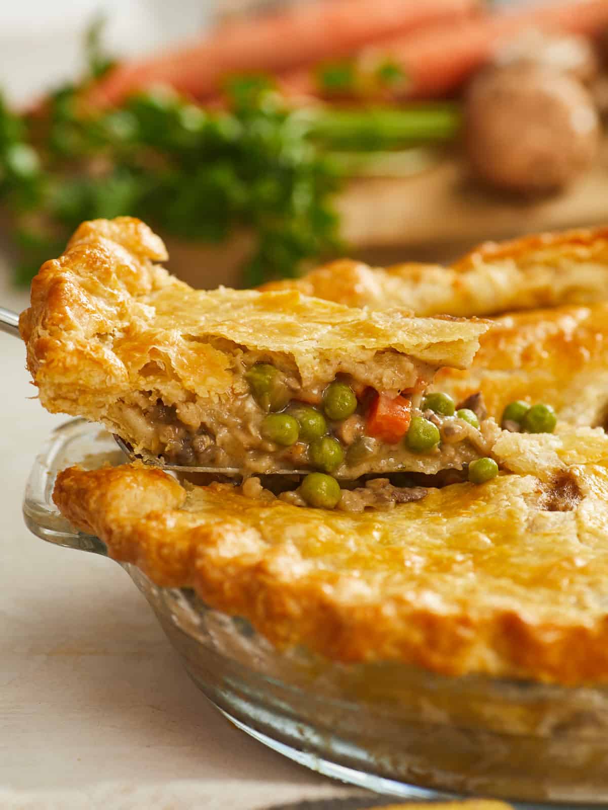 Side view of a slice of vegetable pot pie being lifted from a pie dish.