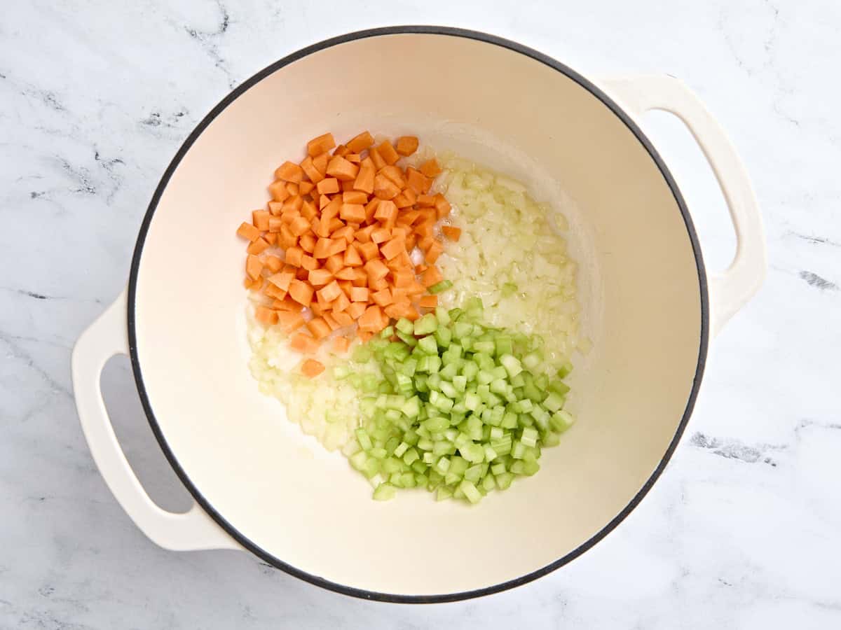 Diced carrots and diced celery in a Dutch oven with sauteed onions.