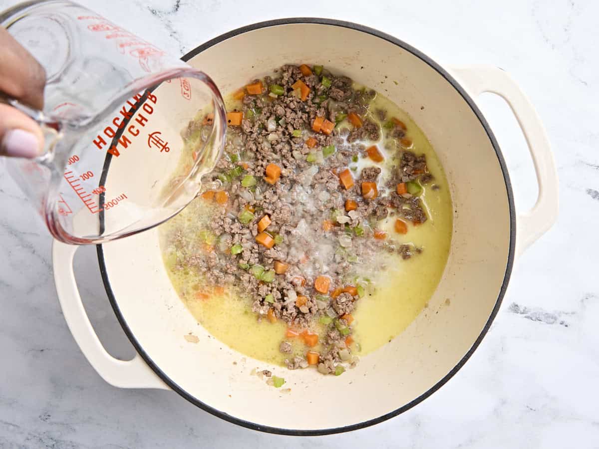 Milk and wine added to a Dutch oven with browned ground beef and sauteed vegetables.