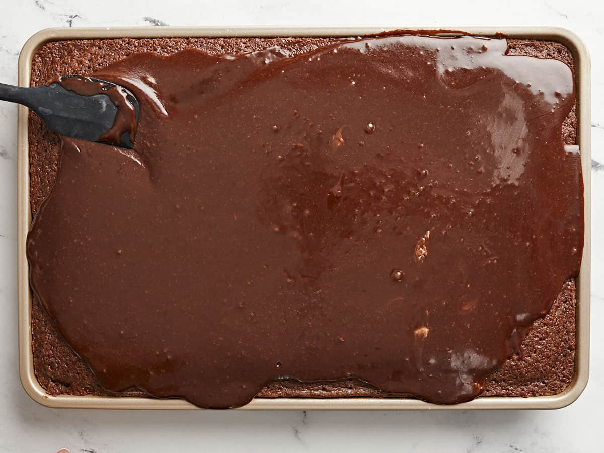 Icing being spread over the baked cake.