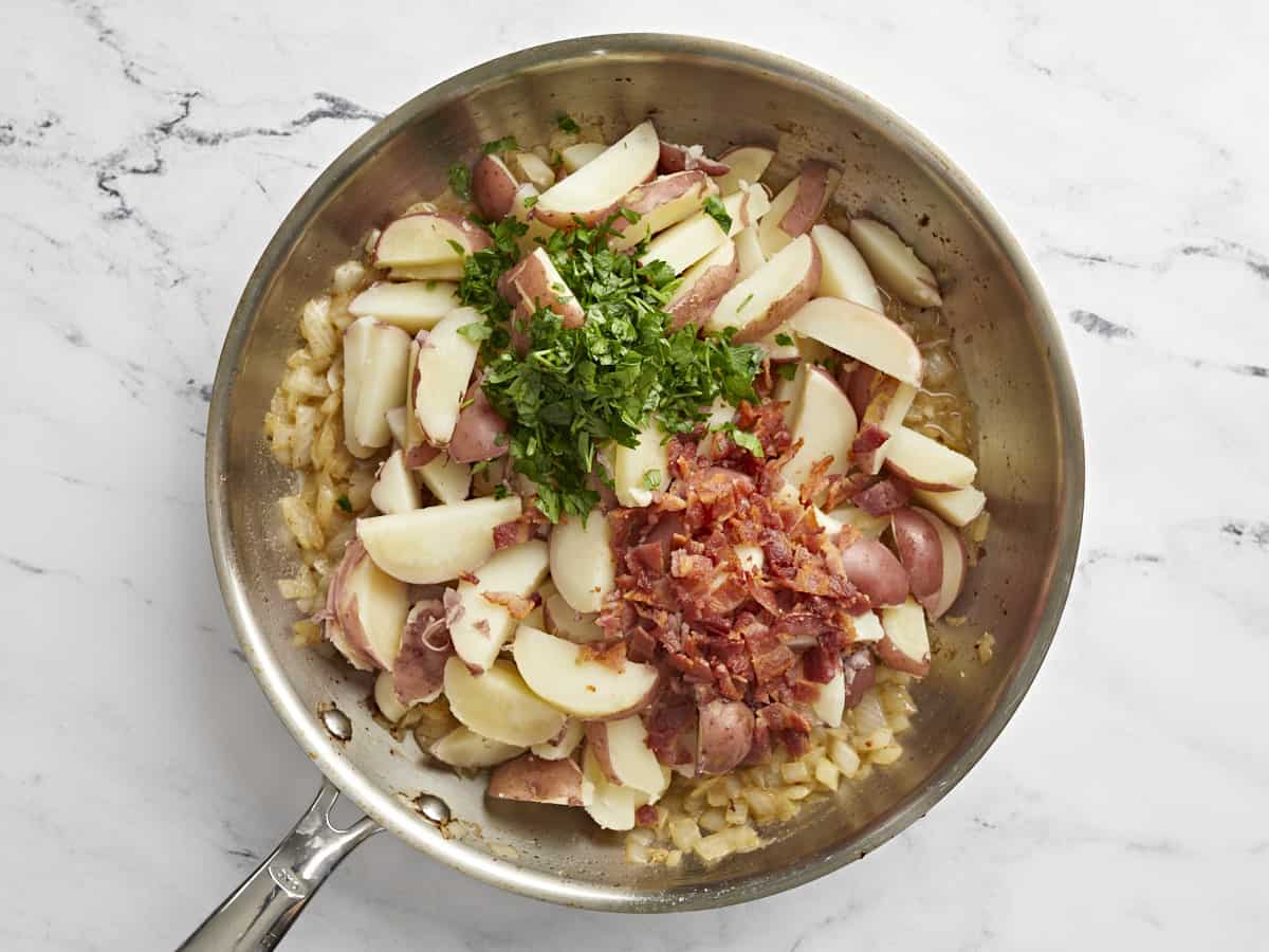 German Potato Salad is tossed in a deliciously sweet and tangy mayo-free dressing with bacon, mustard, and vinegar. Perfect for potlucks! BudgetBytes.com Sliced potatoes, parsley, and bacon added back to the skillet.