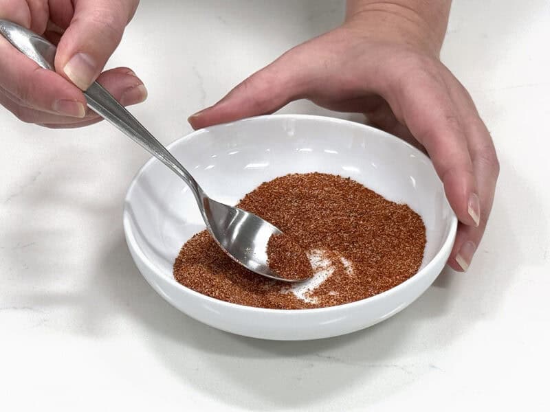 recipe developer stirring homemade burger seasoning in a bowl