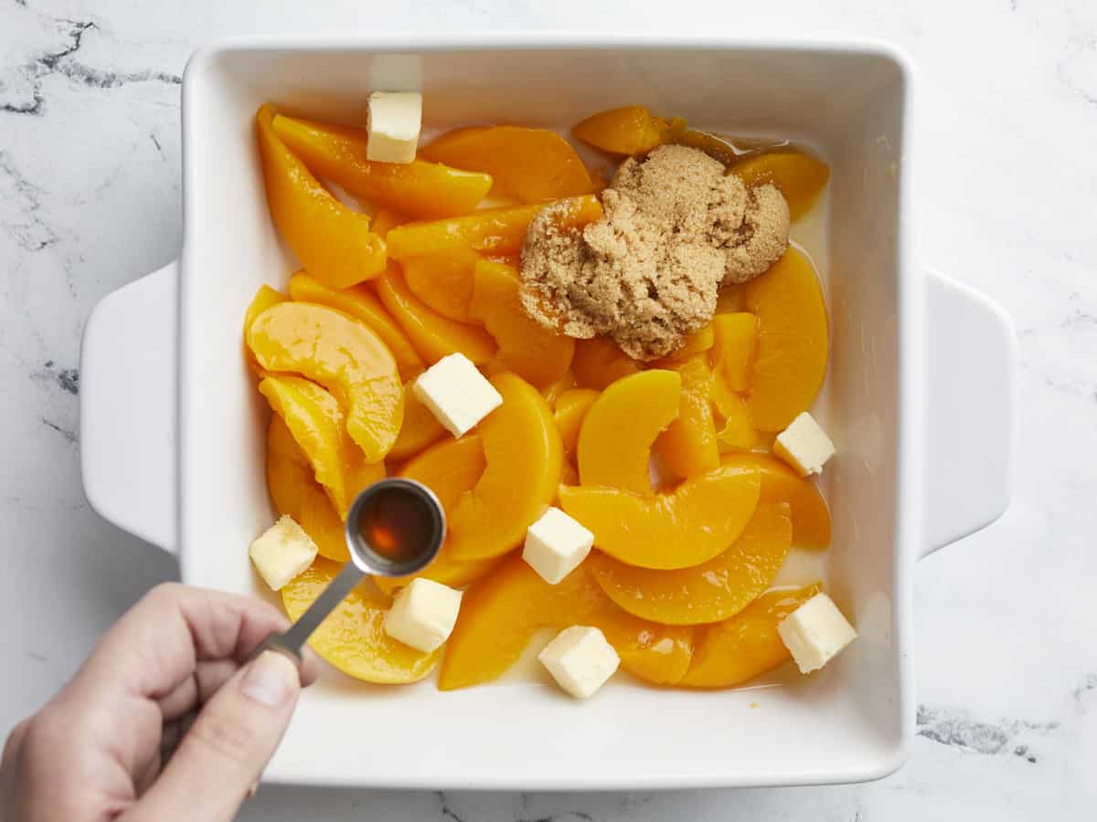 Canned peaches, brown sugar, and cubed butter in a baking dish.