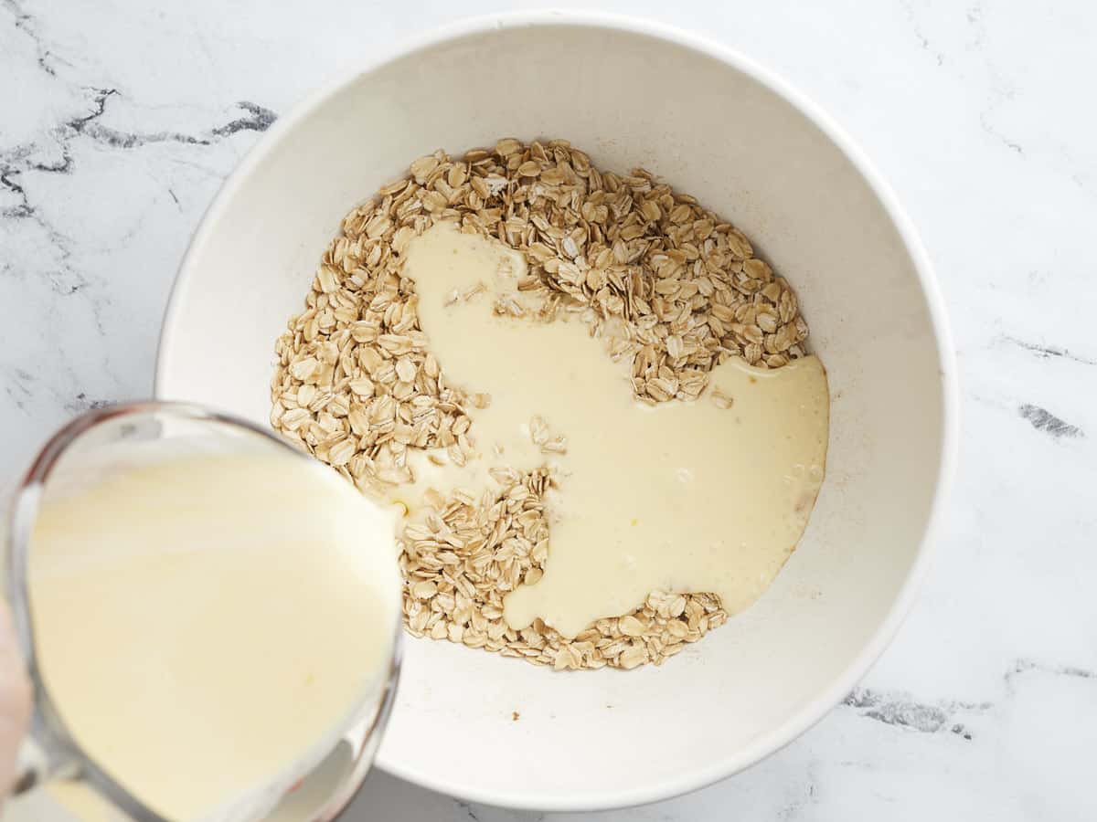 Pouring a mixture of peach juice and cream into the oats.
