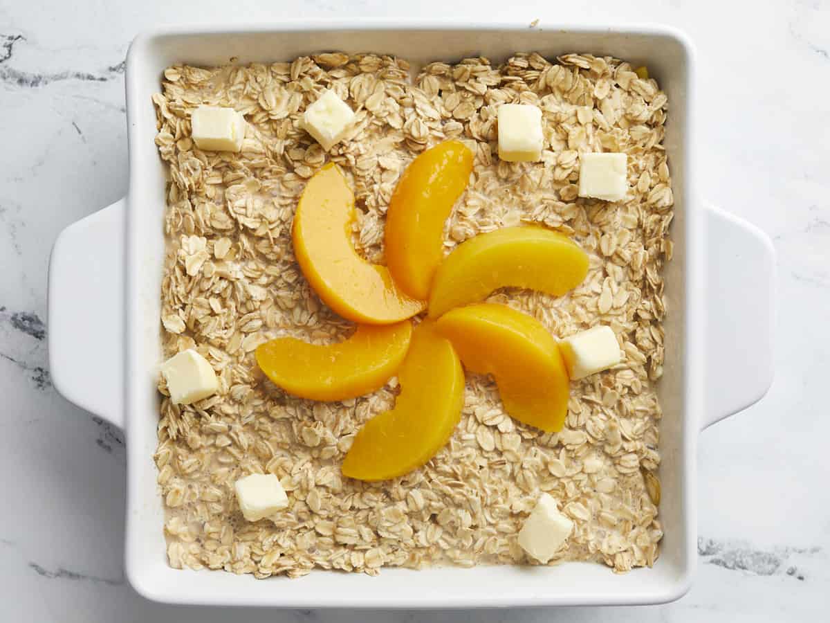 Overhead shot of unbaked Peach Baked Oatmeal in a white baking dish.