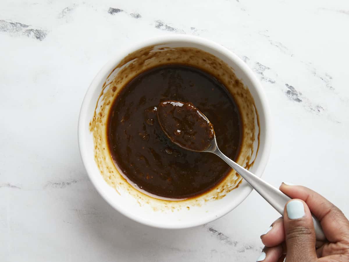 Overhead shot of a bowl of chicken sauce in a white bowl with a spoon.