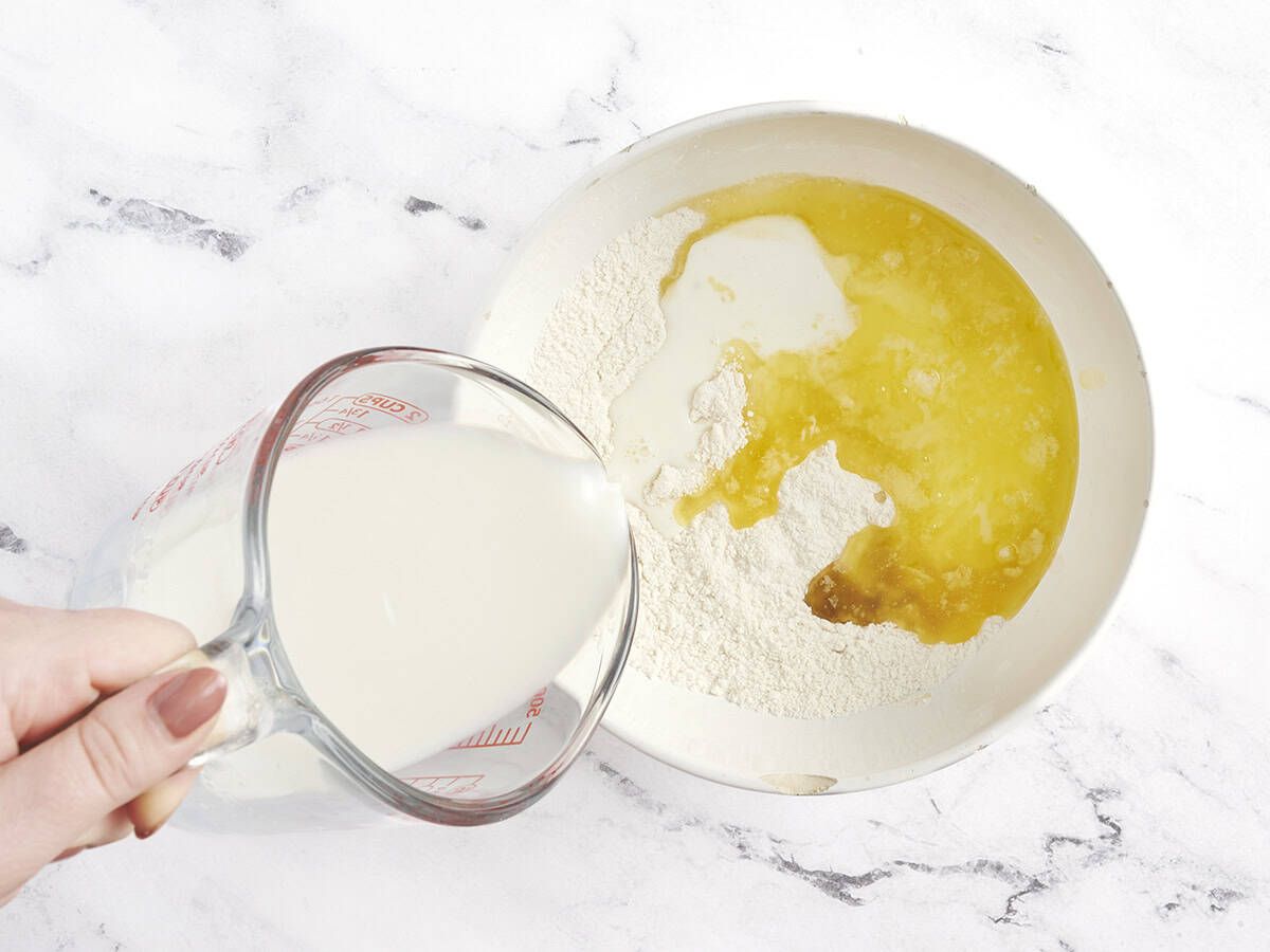 Milk and melted butter being poured into the dry ingredients for peach cobbler.