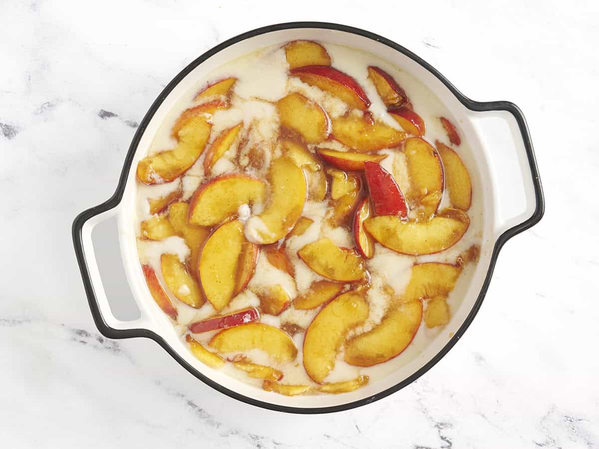 Peach mixture added to the batter for cobbler in an oven dish.