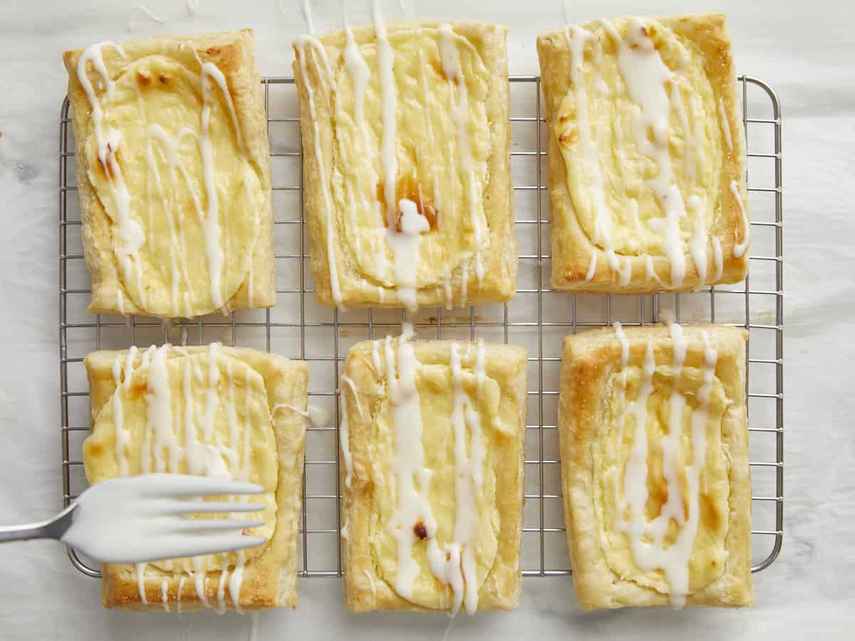 Overhead shot of cheese danish being spinkled with icing.