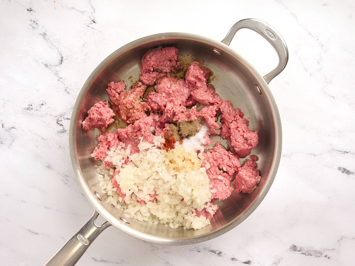 Minced onion, ground beef and spices in a skillet.