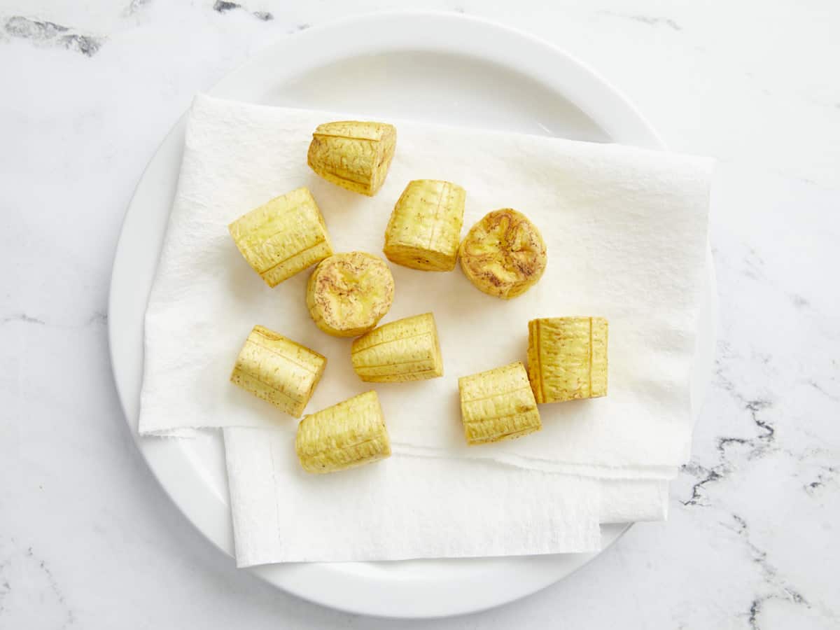Overhead shot of slices of green plantain that have been fried once.