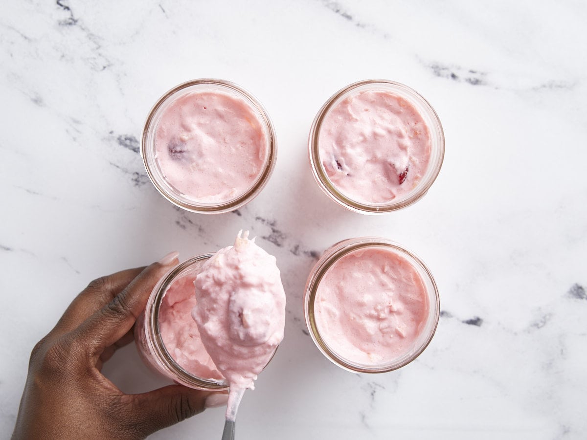 Jello salad in 4 mason jars with one jar being filled
