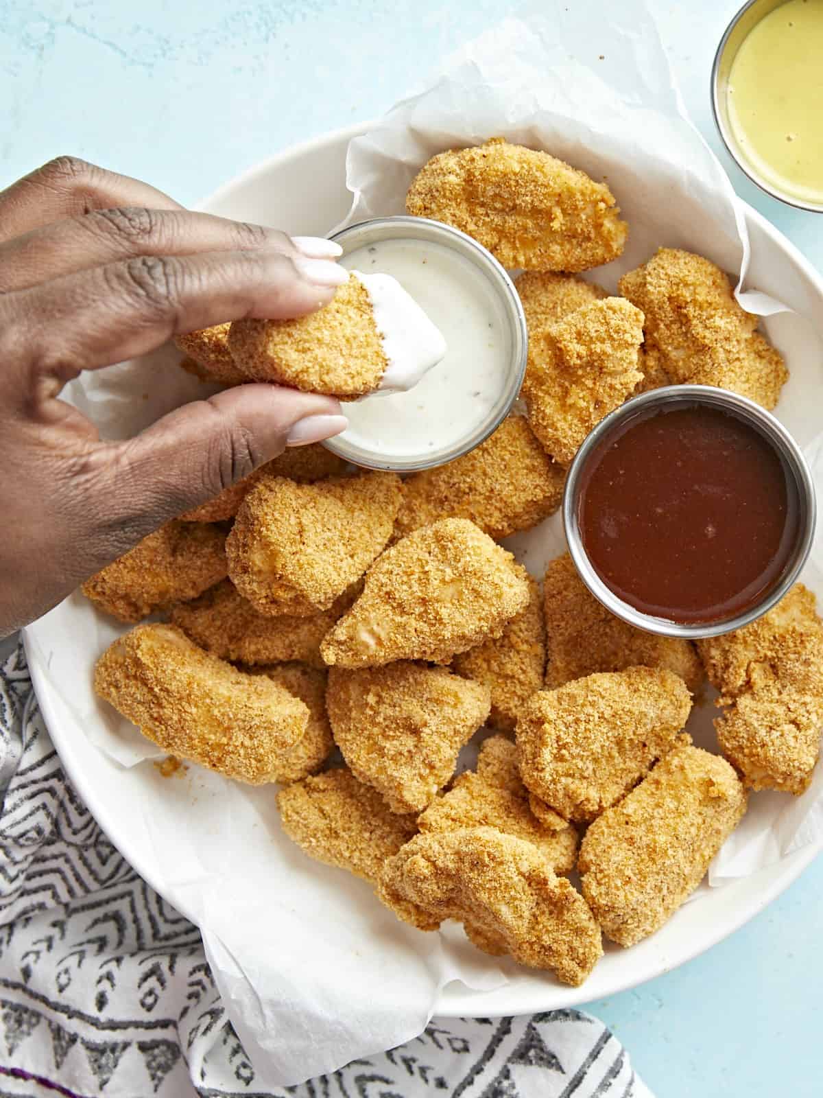 Plated Air Fryer Chicken Nuggets with one nugget being dipped into ranch sauce.