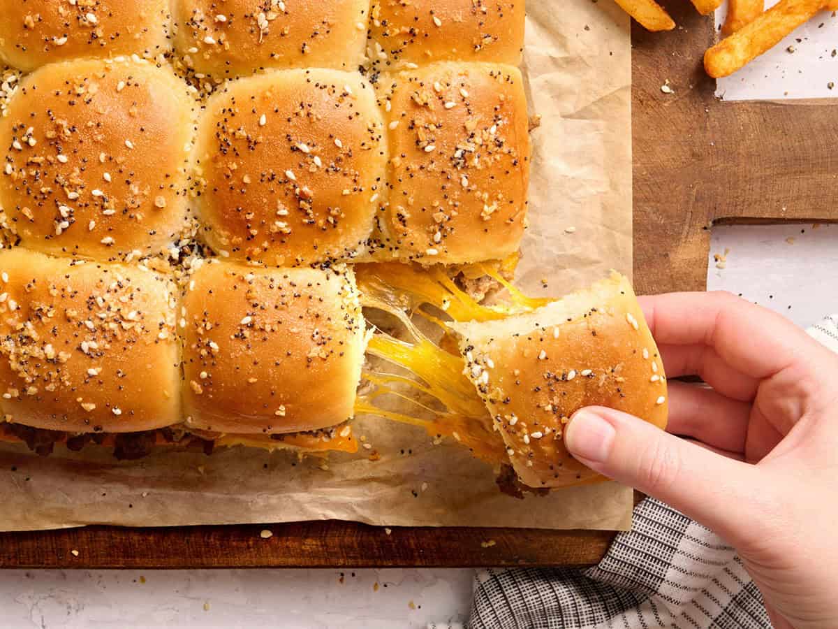 A hand pulling a slider with a cheese pull.