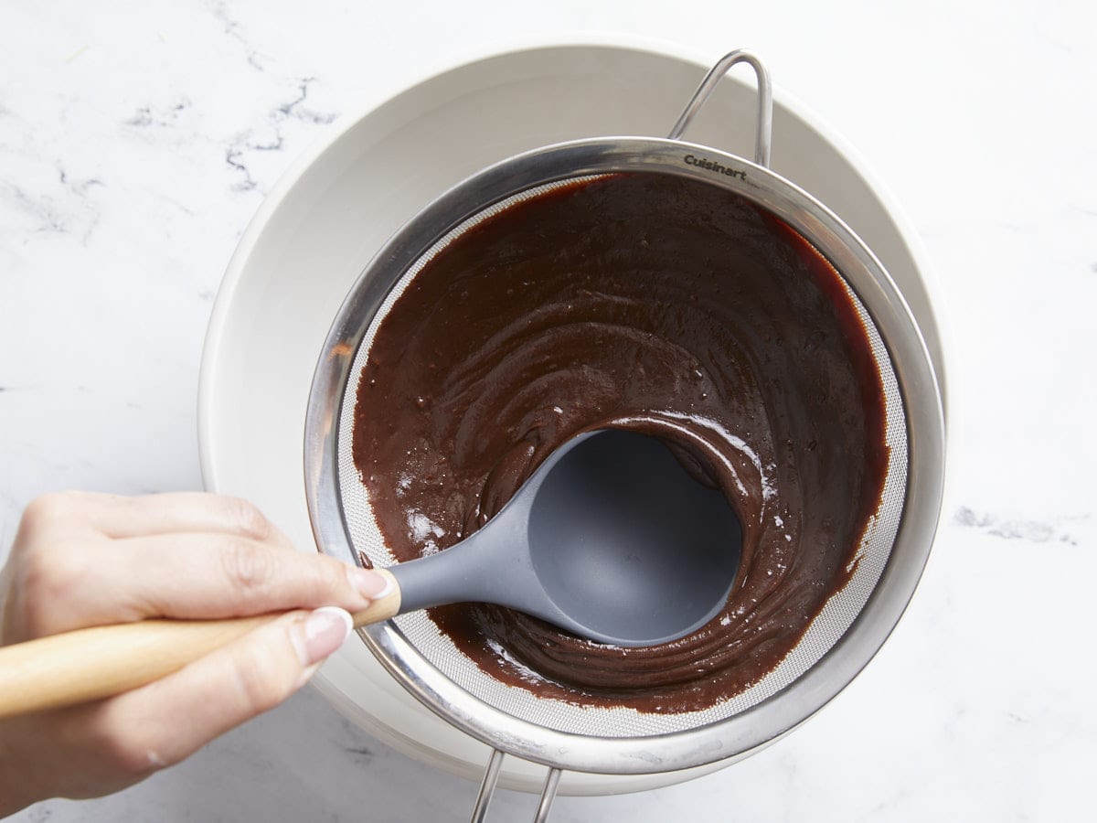 Chocolate being pushed through a sieve.