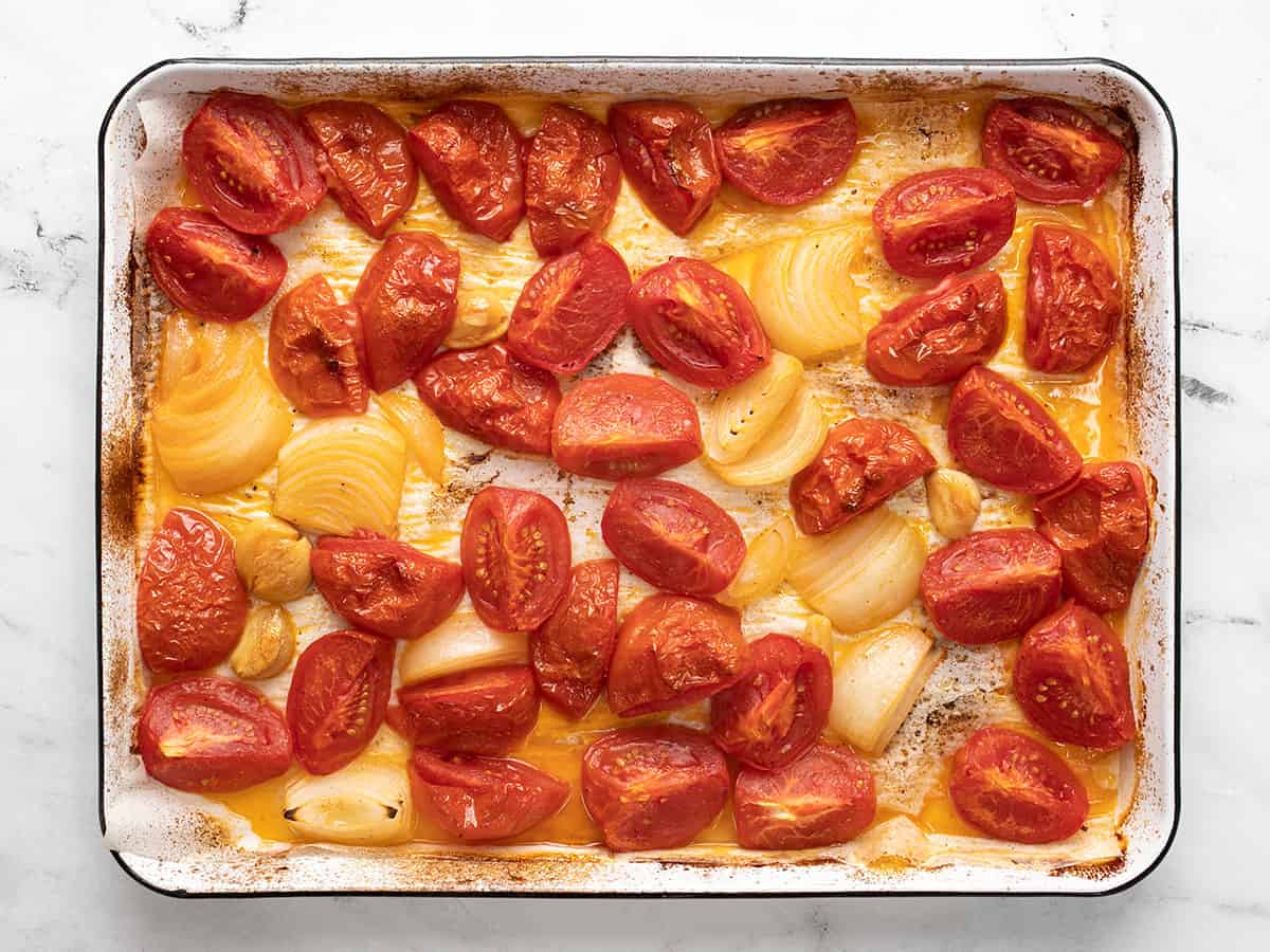 Roasted tomatoes, onions, and garlic on the sheet pan.
