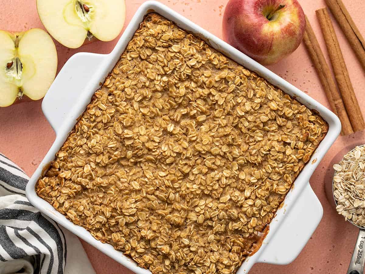 Overhead view of a casserole dish full of apple cinnamon baked oatmeal with ingredients on the sides.