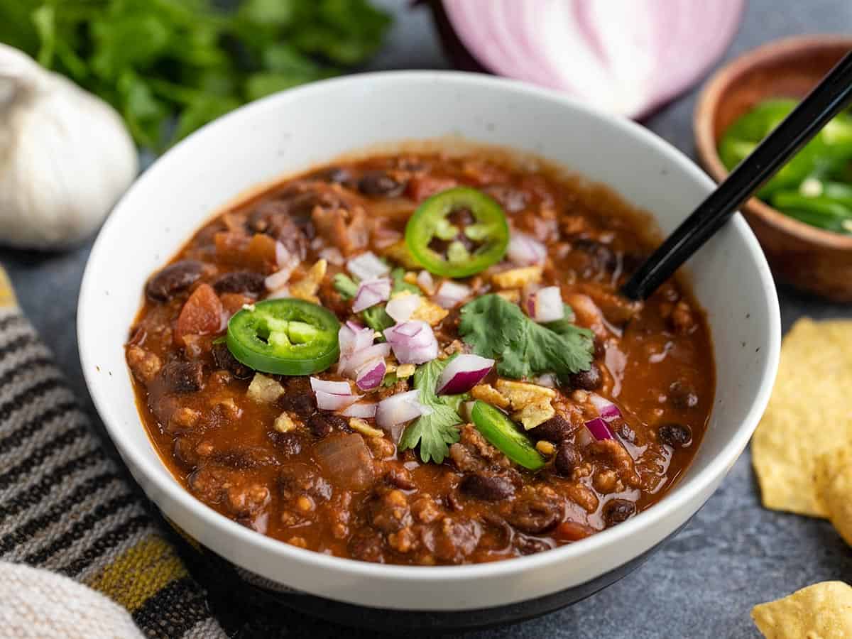This easy and comforting black bean chili is rich, full of warm chili spices, and fast enough to pull together on a busy weeknight. Budgetbytes.com Side view of a bowl full of black bean chili with a spoon in the center.