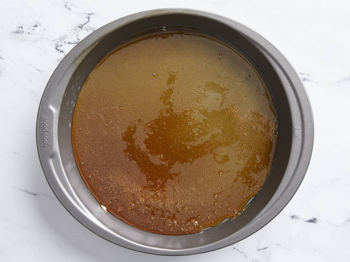 Caramel poured into the bottom of a cake pan.