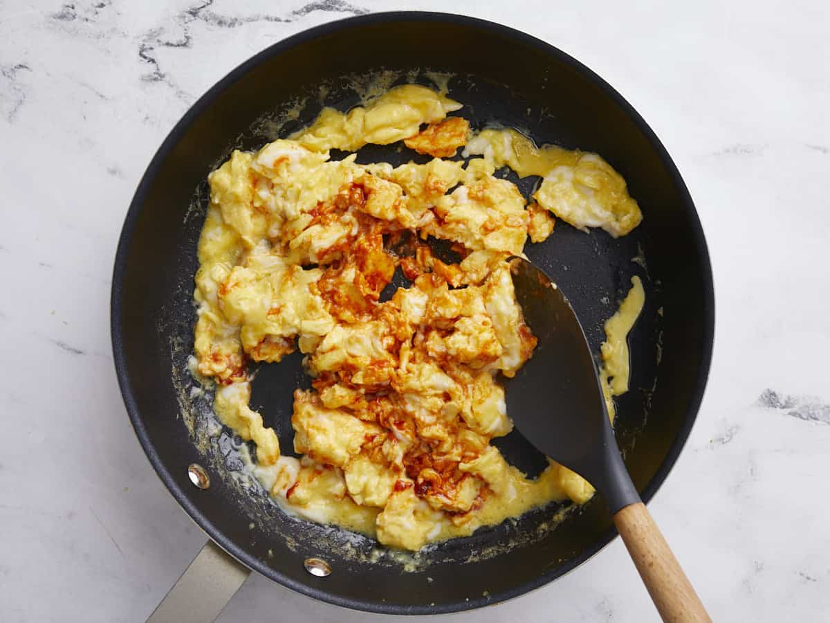 Half-scrambled eggs in a skillet with gochujang added.