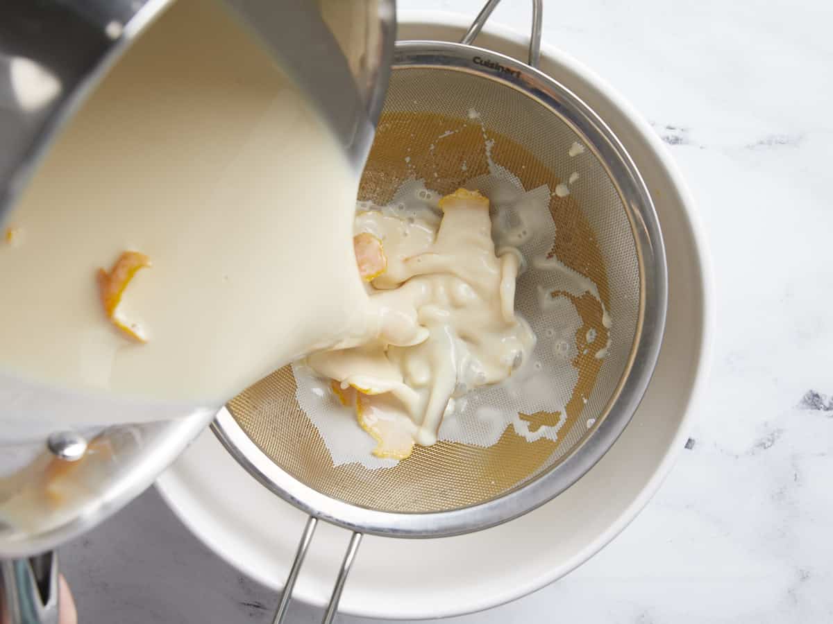 Steeped milk being poured through a sieve.