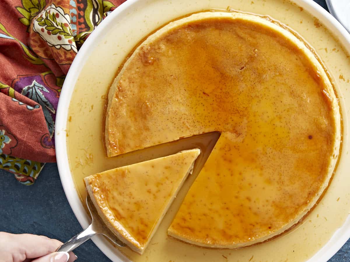 Overhead view of flan being served, one slice being lifted.