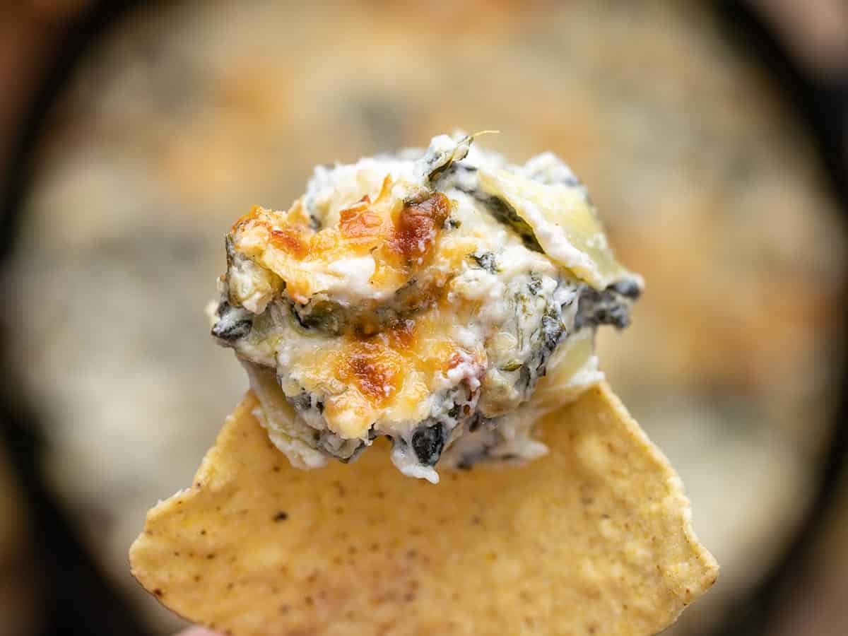Double Spinach Artichoke Dip is PACKED with spinach, three types of cheese, and just enough spice to tingle your taste buds. It’s the classic dip, elevated. BudgetBytes.com Close up of spinach artichoke dip on a tortilla chip.