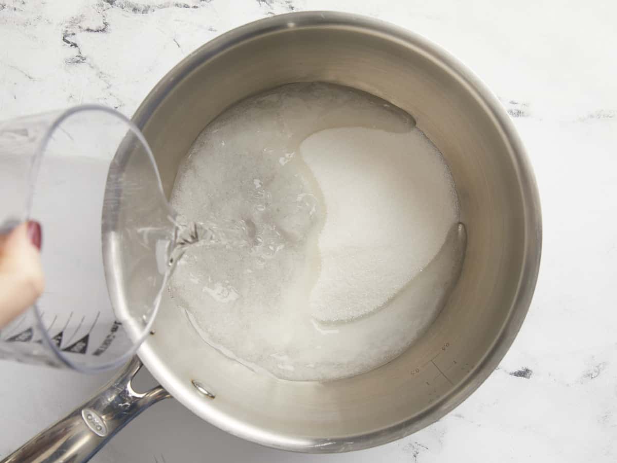 Water being poured into a pot with sugar.