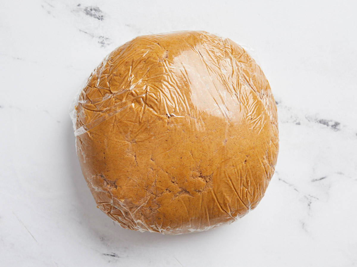 Ball of cookie batter wrapped in plastic.