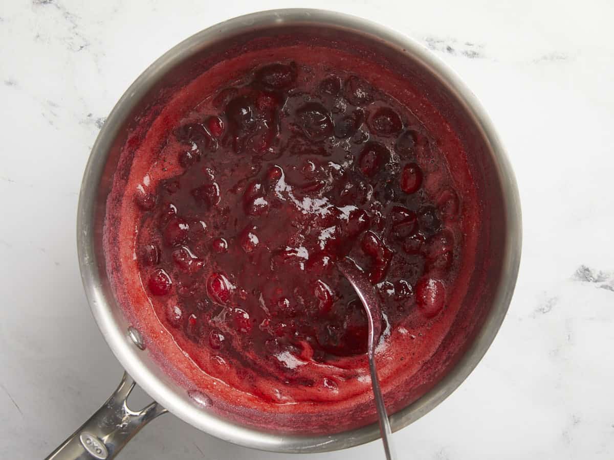 Thickened cranberry sauce being stirred.