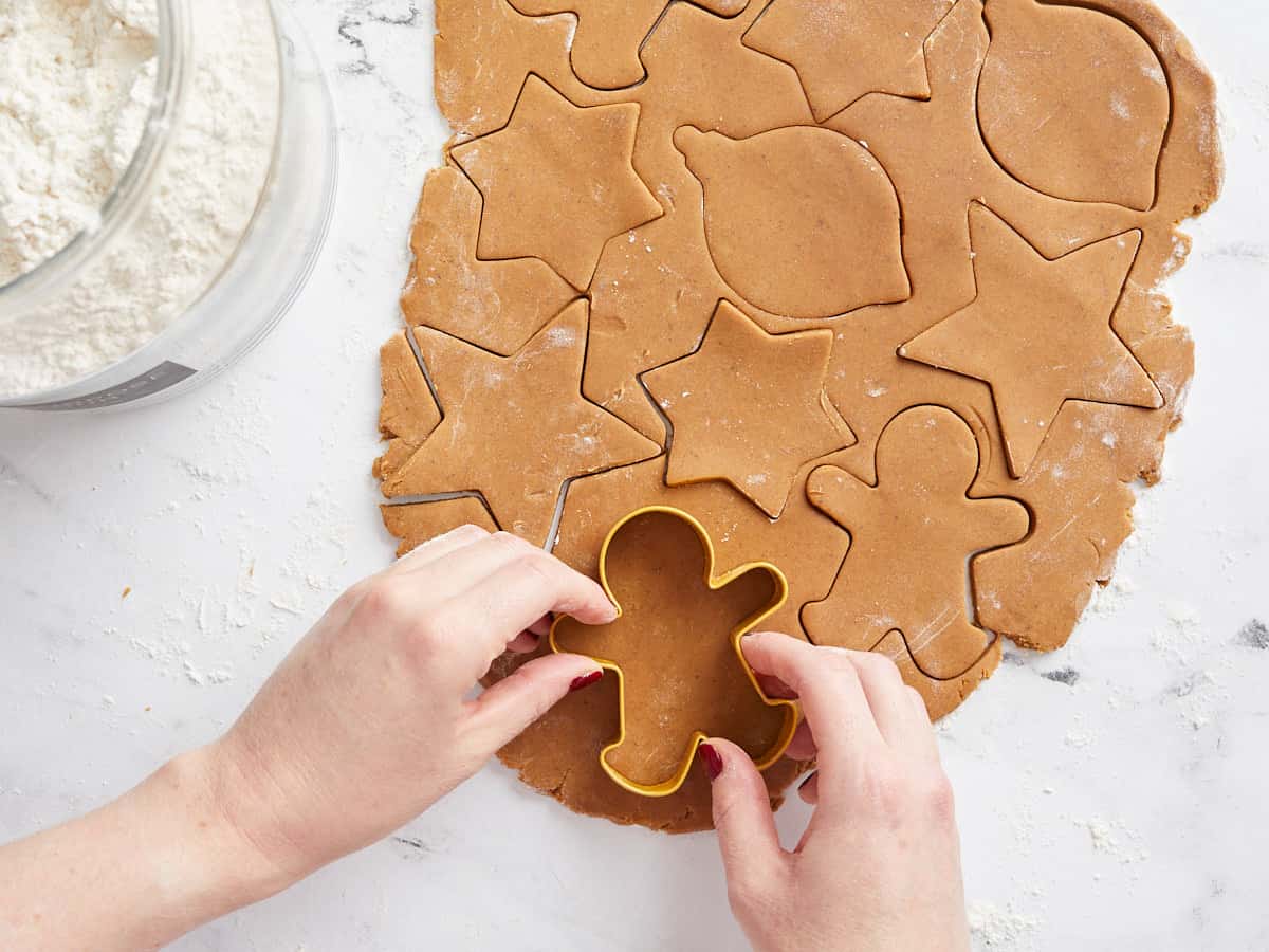 Gingerbread cookie batter rolled out and being cut with a cookie cutter.