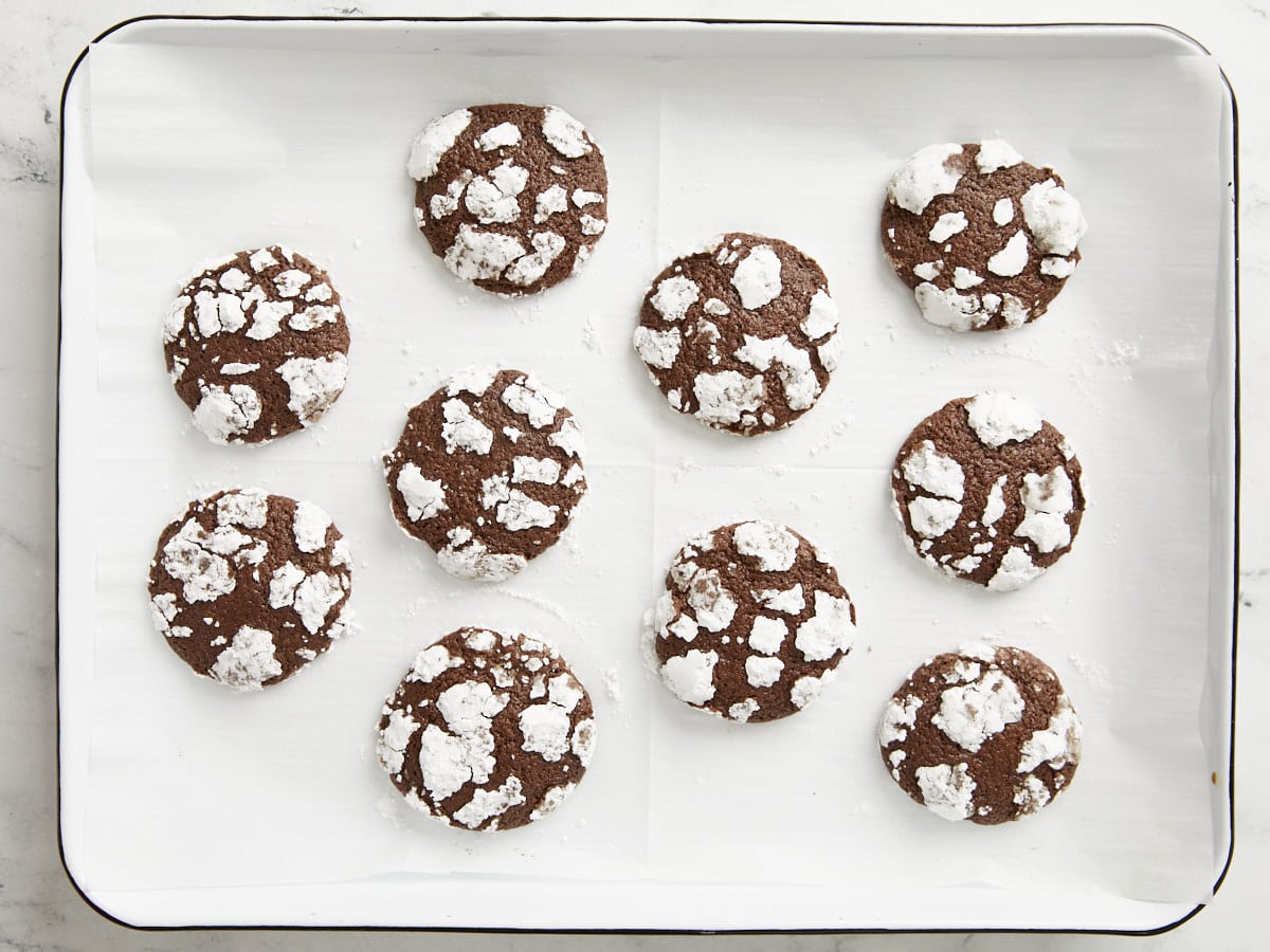 Baked chocolate crinkle cookies on the baking sheet.