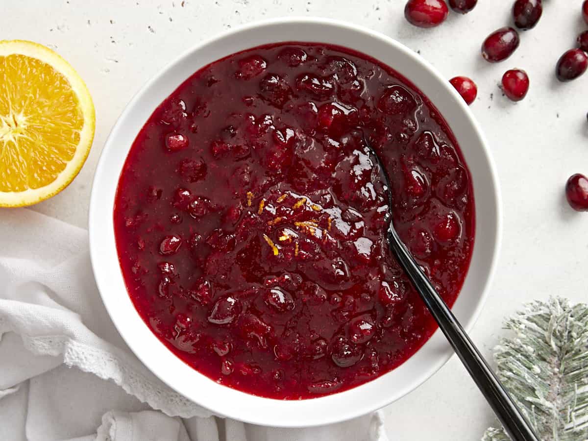 This simple classic cranberry sauce only requires three ingredients but has enough flavor to add excitement to your holiday meal. Budgetbytes.com Overhead view of cranberry sauce in a bowl with orange zest and a spoon.
