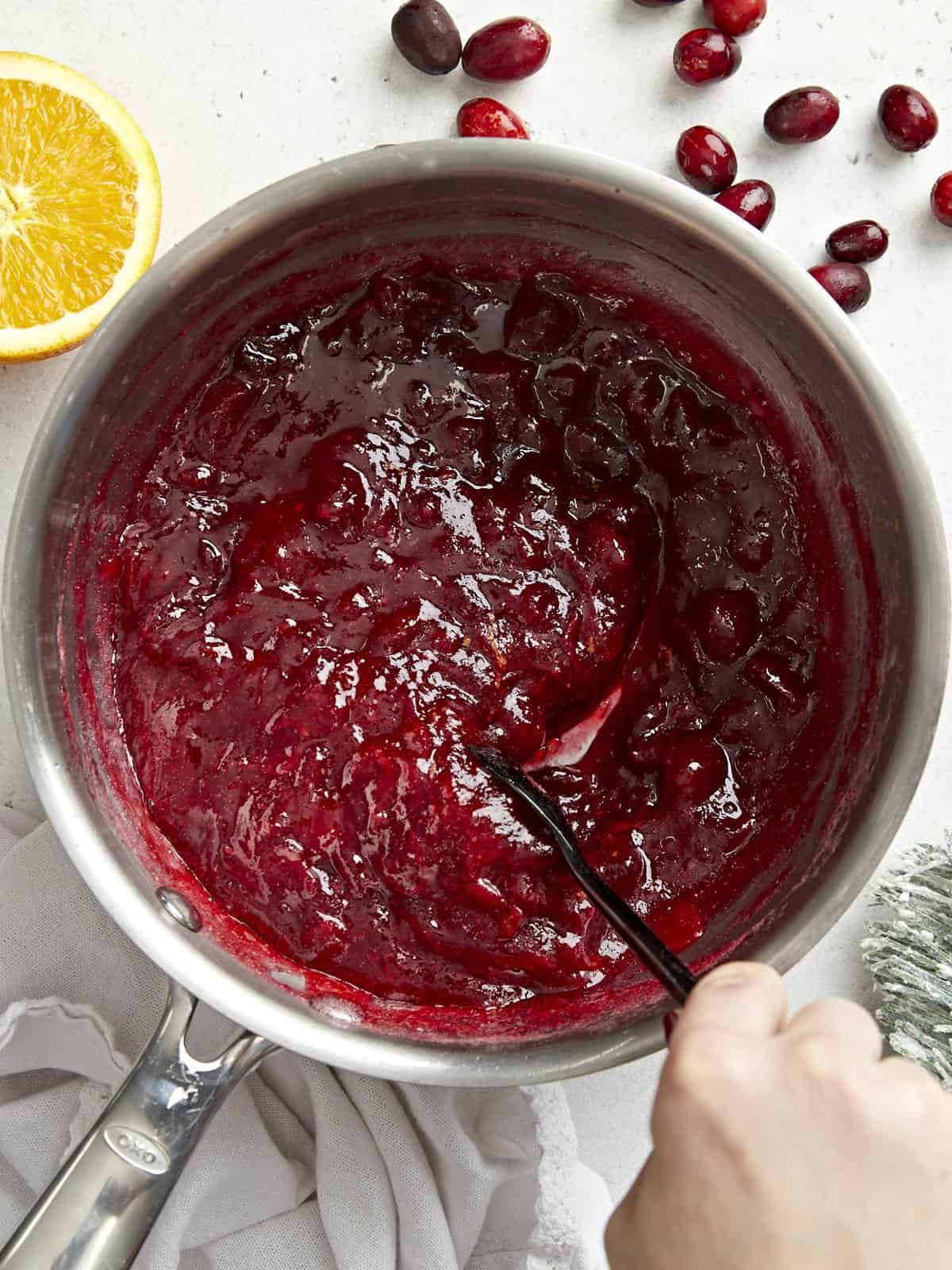 This simple classic cranberry sauce only requires three ingredients but has enough flavor to add excitement to your holiday meal. Budgetbytes.com Overhead view of a pot full of homemade cranberry sauce being stirred.