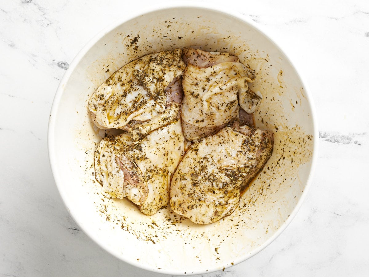 Seasoned chicken thighs in a bowl.