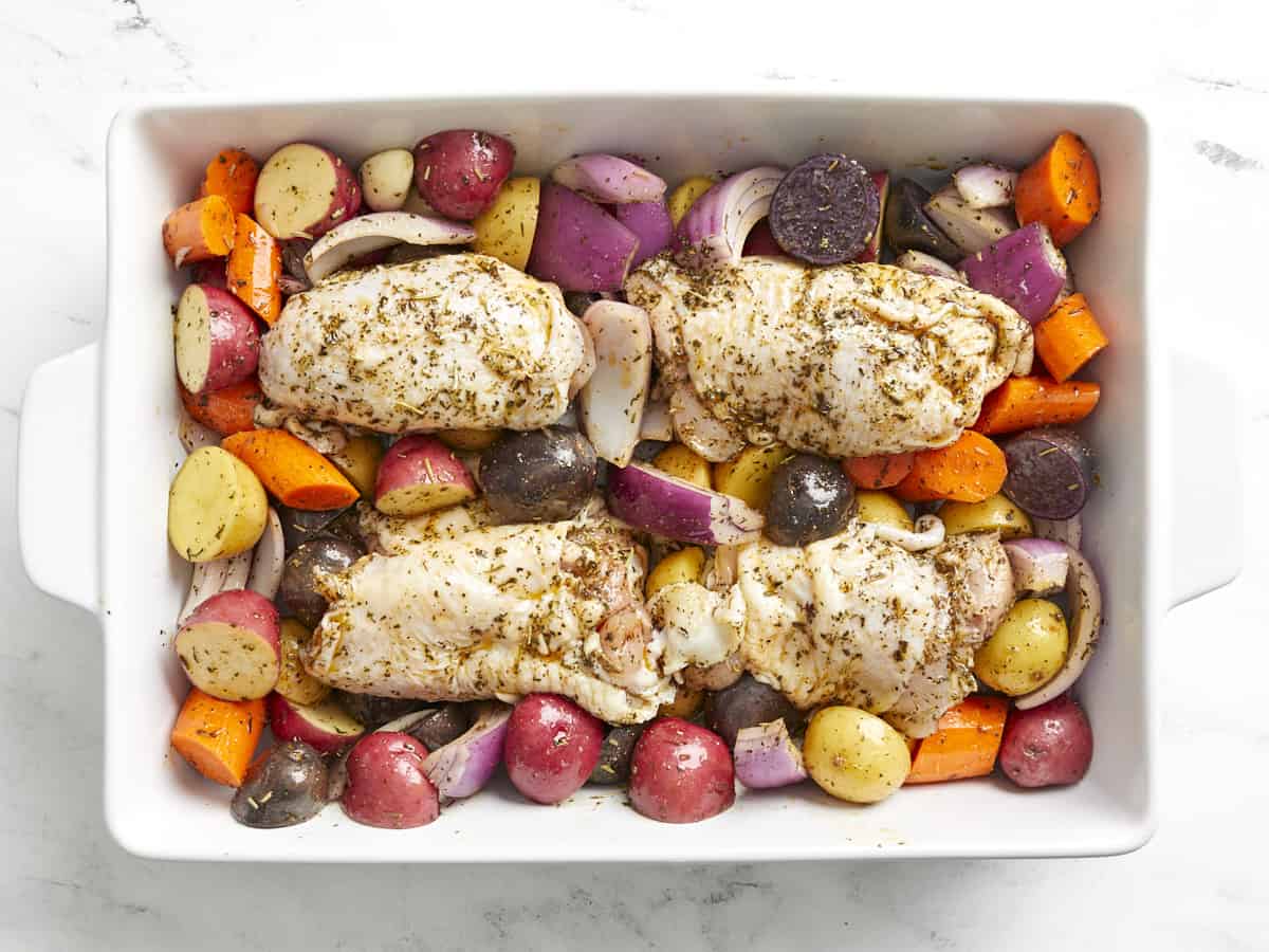 Chicken thighs in the casserole dish with the vegetables.