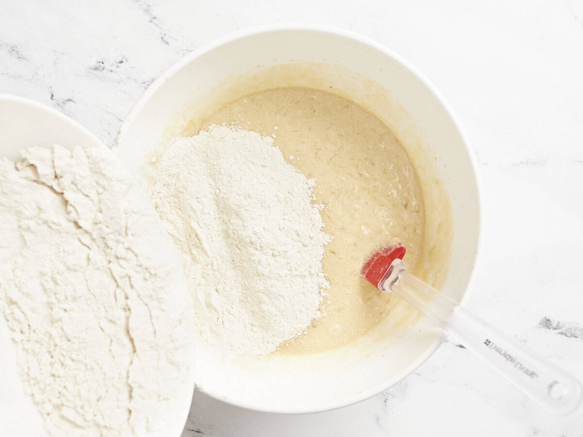 Dry ingredients being poured into the bowl of wet ingredients.