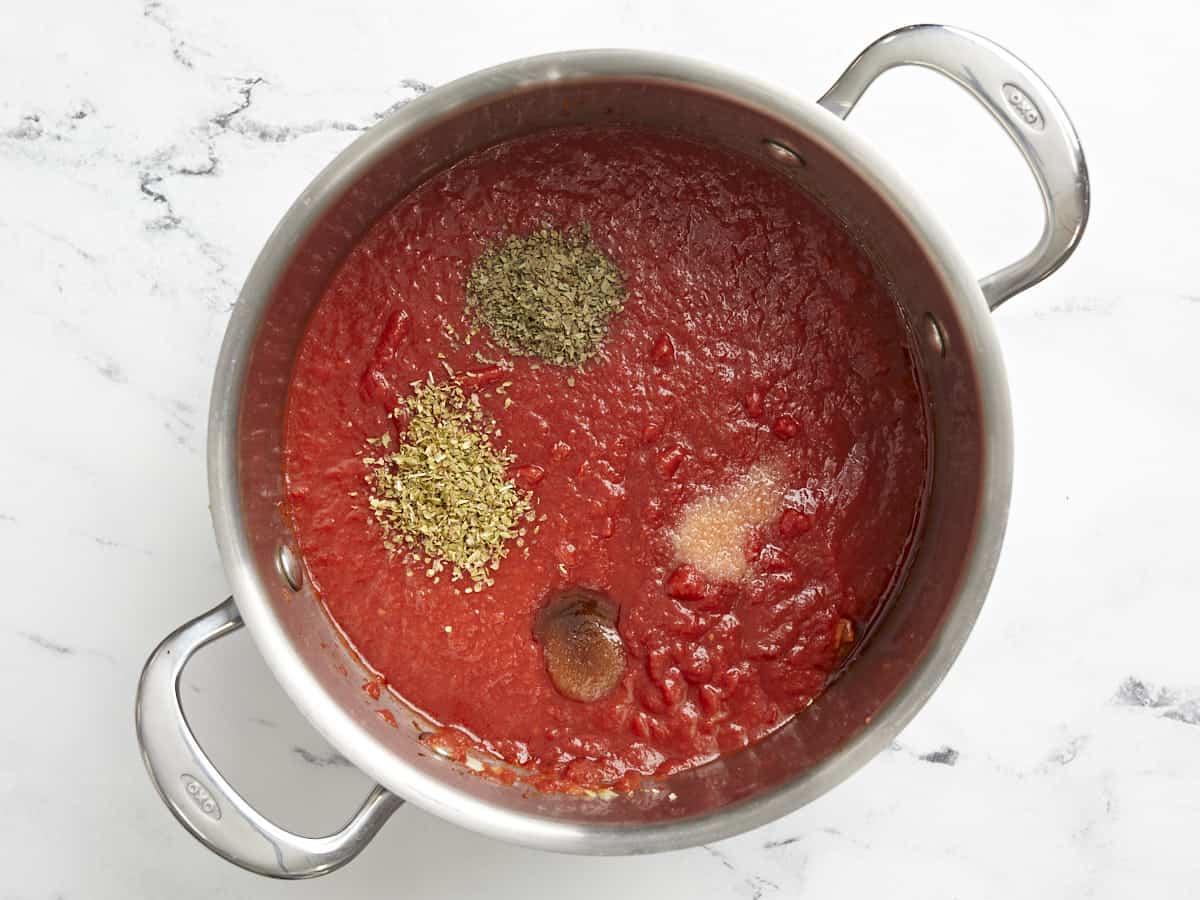 Crushed tomatoes, sugar, and herbs added to the pot.