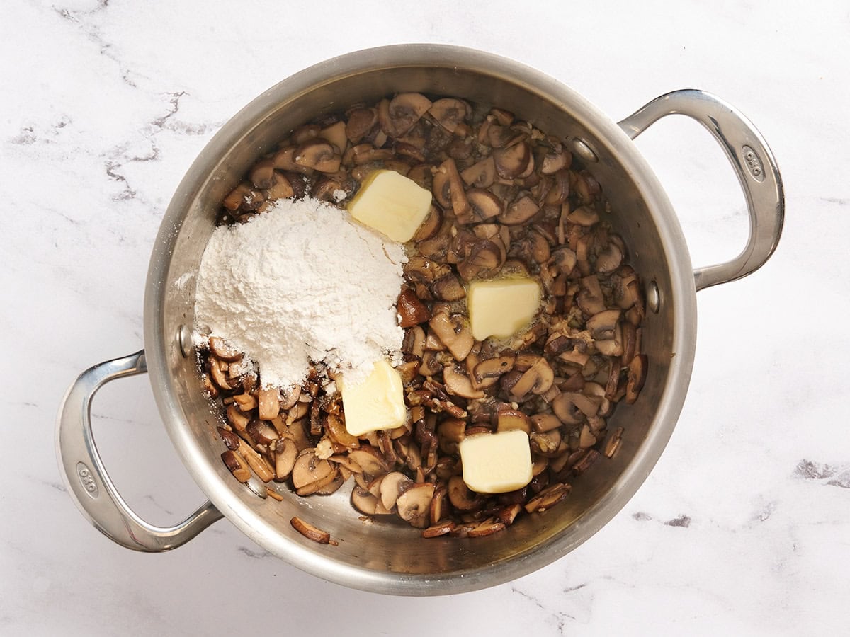 Butter and flour added to a pan of sauteed mushrooms.