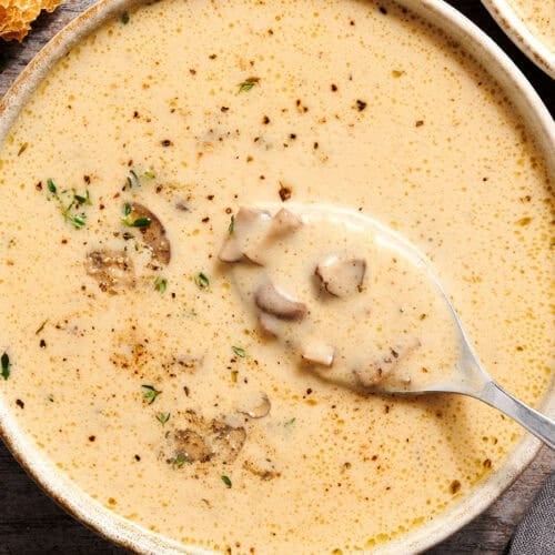 Overhead view of creamy mushroom soup in a bowl with a spoon.