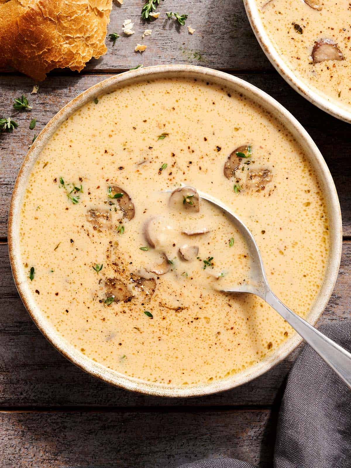 This rich and Creamy Garlic Mushroom Soup is perfect for fall with it's deep earthy flavors. Serve with crusty bread for dipping! Budgetbytes.com Overhead view of creamy mushroom soup in a bowl with a spoon.