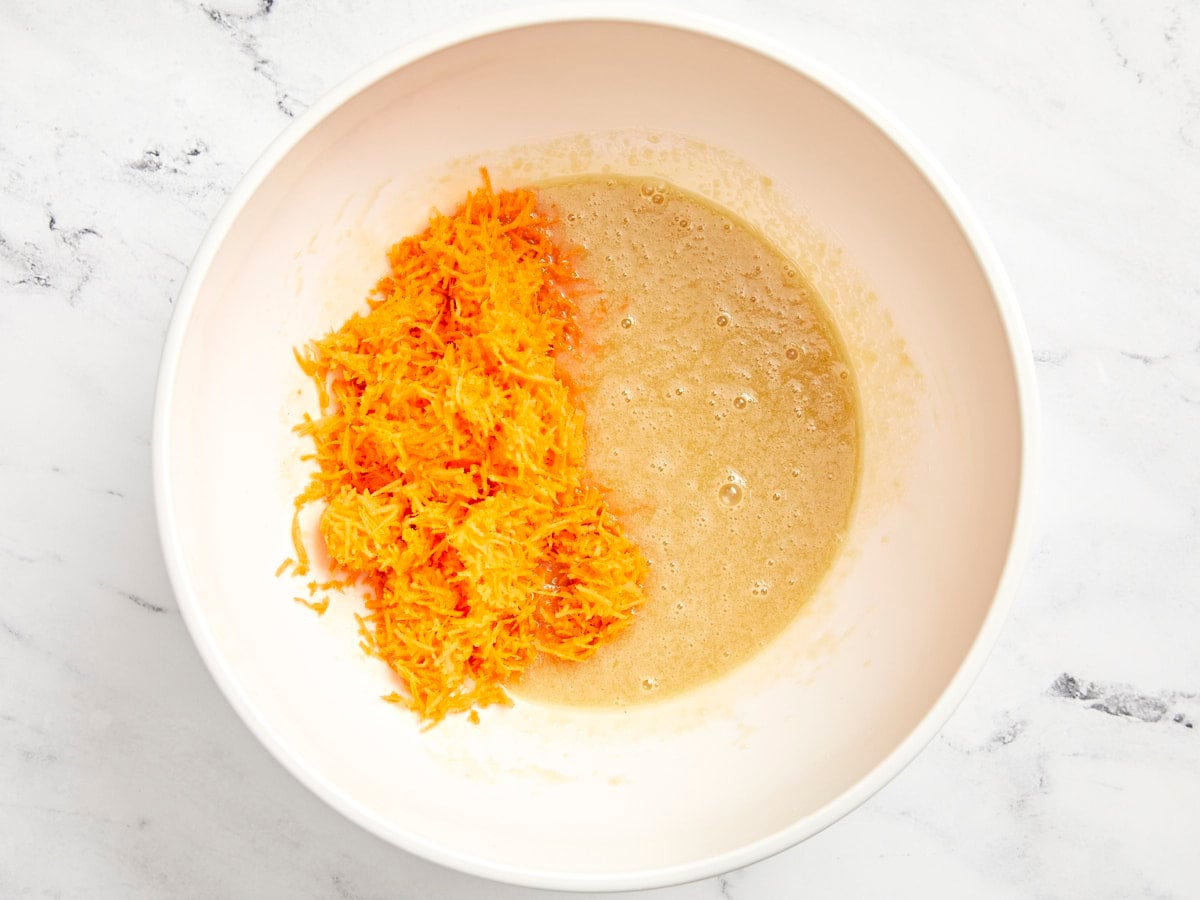 Grated carrots added to mixed wet ingredients.