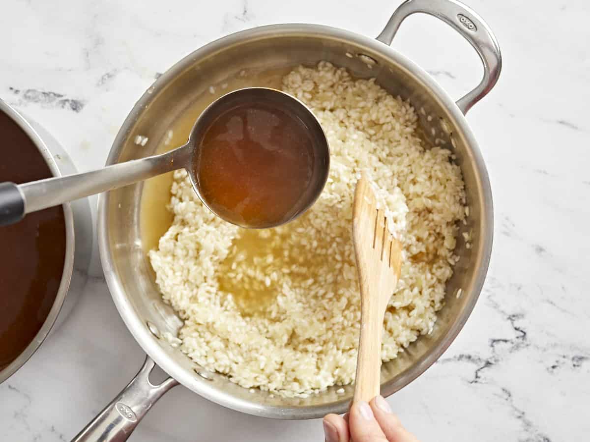 vegetable broth added to rice in a pan.