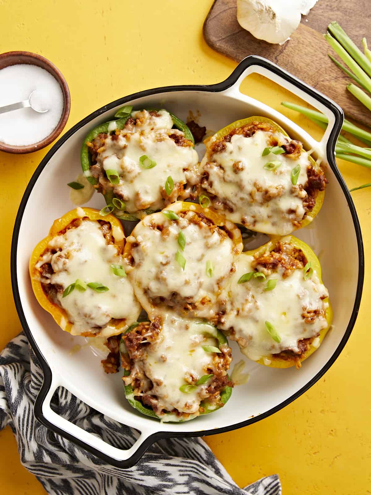 Super flavorful chorizo is the key to keeping these Chorizo Stuffed Bell Peppers simple and delicious enough for a weeknight dinner. BudgetBytes.com Overhead view of chorizo stuffed bell peppers in a baking dish on a yellow background.